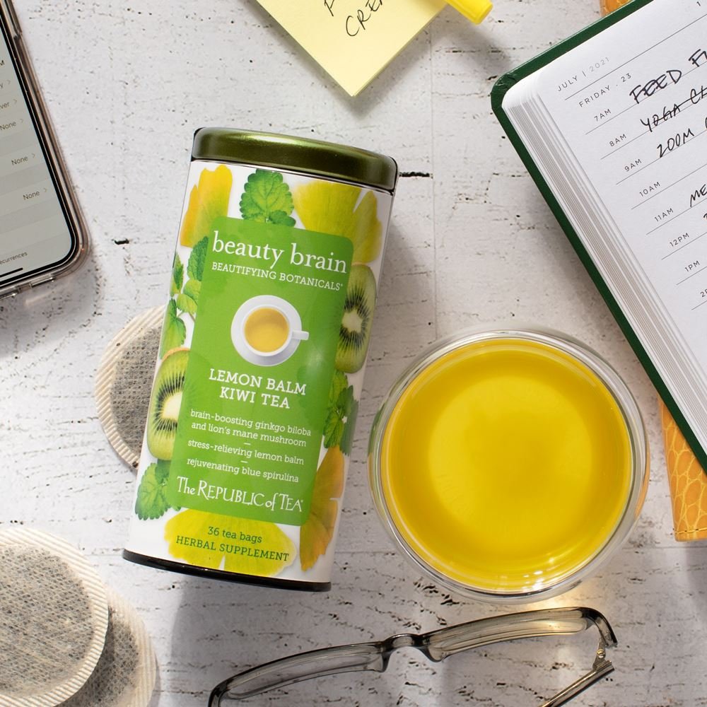 Tin of Beauty Brain, teacup, glasses and book